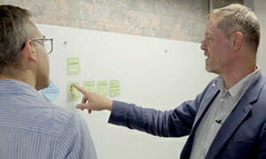  2 men working at a whiteboard